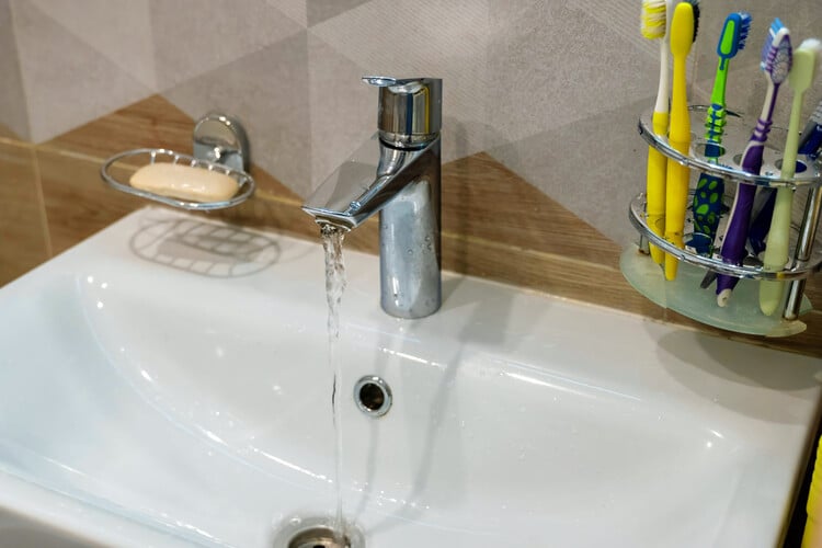 Water running from faucet into sink in modern bathroom