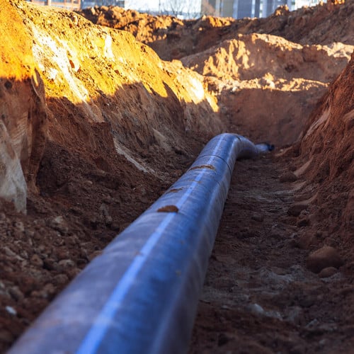 Plastic water line is in the trench in the direction under a blue sky residential buildings